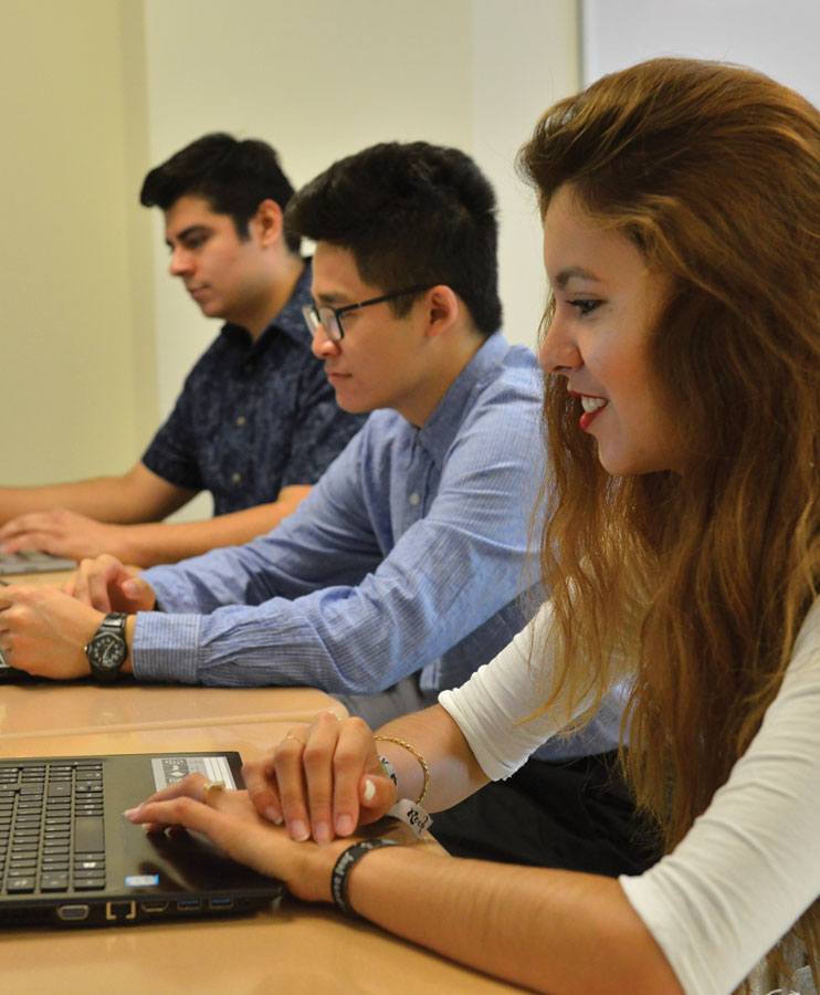 Three business students working on laptops