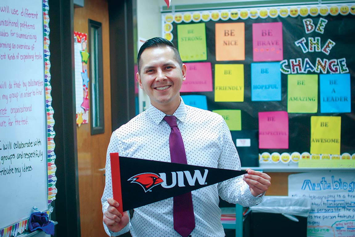 Student holding UIW pennant in classroom